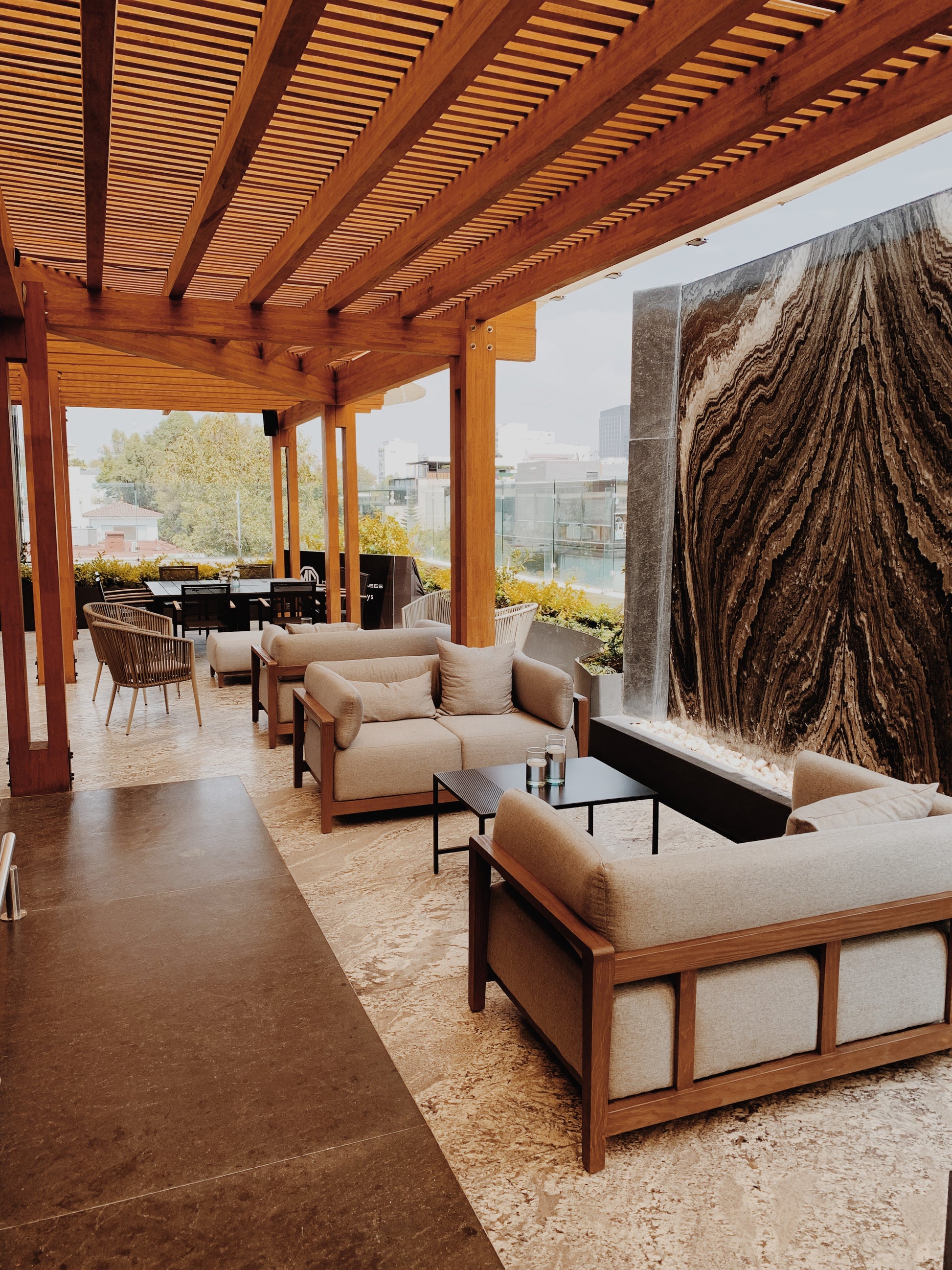 Outdoor patio with wooden pergola, furniture, and a cityscape view.